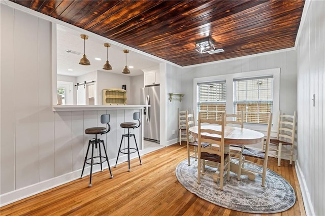 dining space with light wood-type flooring, crown molding, a barn door, and wooden ceiling