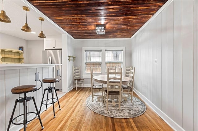 dining space featuring light hardwood / wood-style floors, crown molding, and wood ceiling