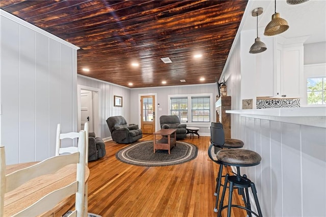 living room with wood-type flooring, wooden walls, ornamental molding, and wooden ceiling