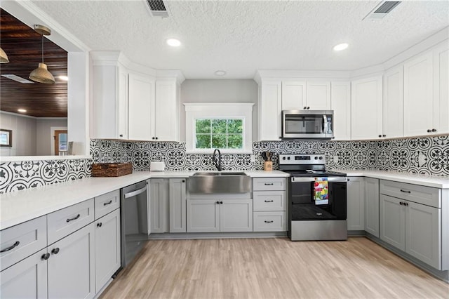 kitchen featuring stainless steel appliances, light hardwood / wood-style floors, gray cabinetry, and sink