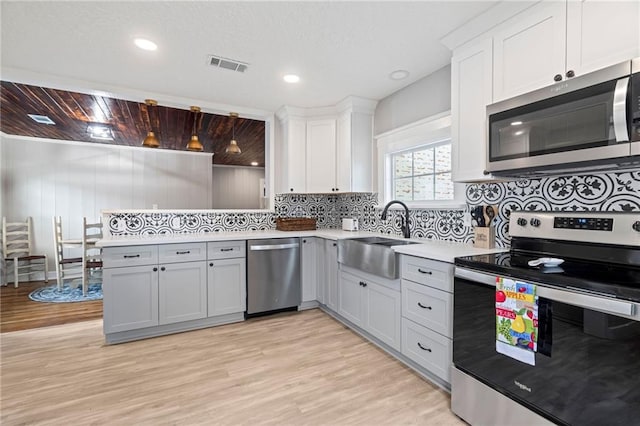 kitchen featuring decorative backsplash, appliances with stainless steel finishes, light wood-type flooring, and sink