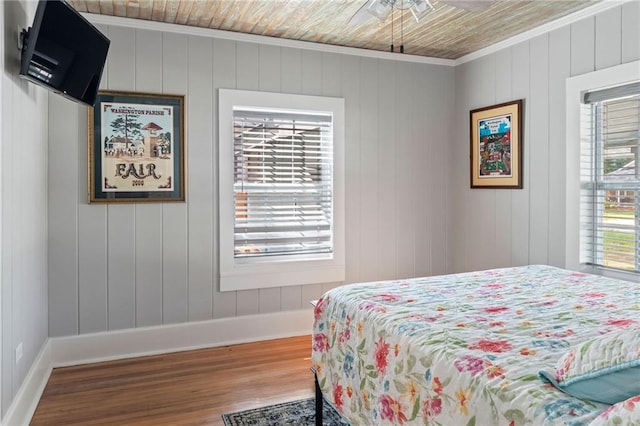 bedroom featuring wood ceiling, wood-type flooring, ornamental molding, and wooden walls