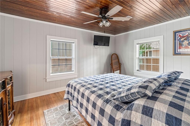 bedroom with wood walls, hardwood / wood-style flooring, ceiling fan, ornamental molding, and wood ceiling