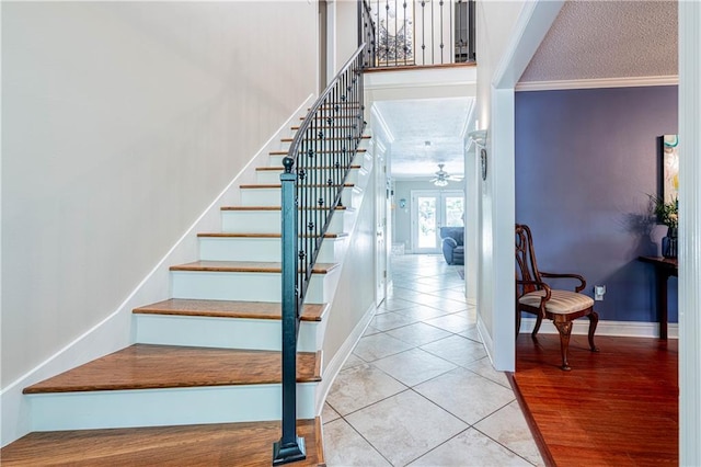 stairway with ceiling fan, a textured ceiling, hardwood / wood-style floors, and crown molding