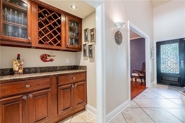 bar with dark stone counters and light tile patterned flooring