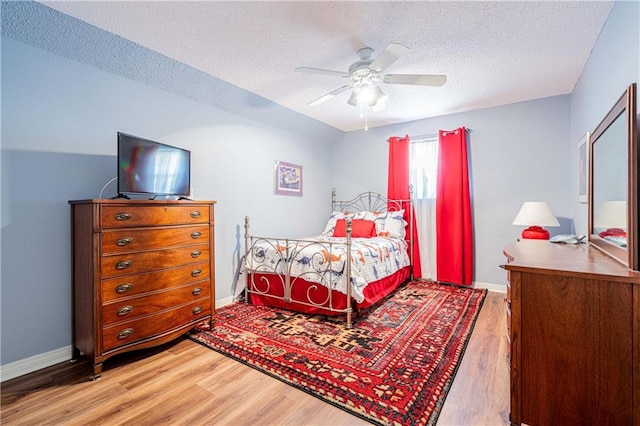 bedroom with light wood-type flooring, ceiling fan, and a textured ceiling