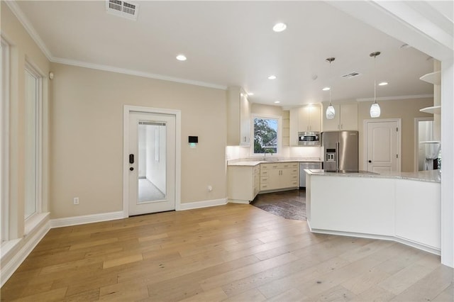 kitchen with appliances with stainless steel finishes, light hardwood / wood-style flooring, ornamental molding, pendant lighting, and sink