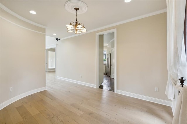 spare room featuring light hardwood / wood-style floors, a notable chandelier, and ornamental molding