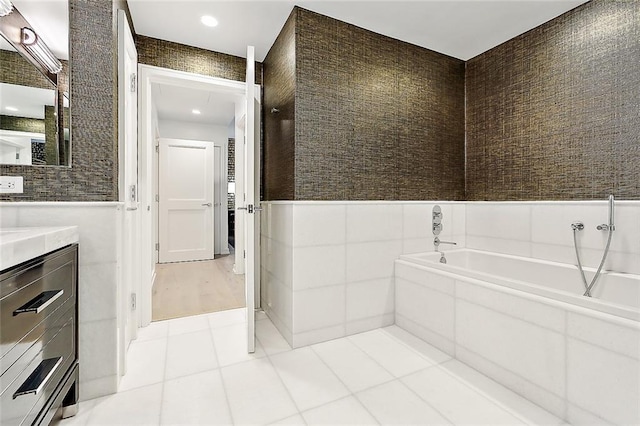 bathroom with tile walls, vanity, tile patterned floors, and a bathtub