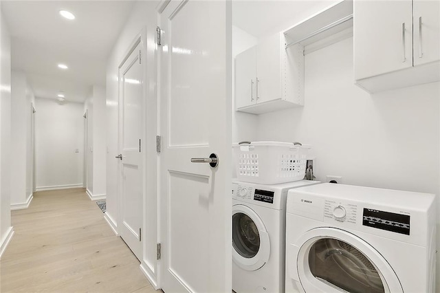 washroom with cabinets, light wood-type flooring, and washing machine and dryer