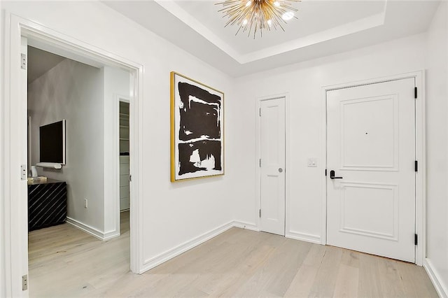 interior space featuring light hardwood / wood-style flooring, a notable chandelier, and a raised ceiling