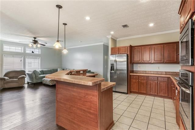 kitchen featuring light hardwood / wood-style flooring, ornamental molding, decorative light fixtures, appliances with stainless steel finishes, and ceiling fan