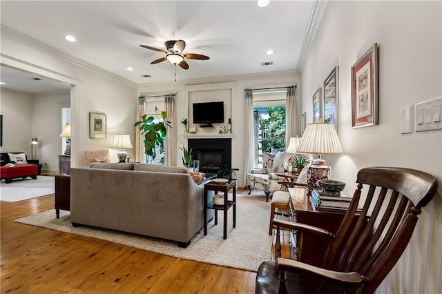 living room with ornamental molding, ceiling fan, and hardwood / wood-style flooring