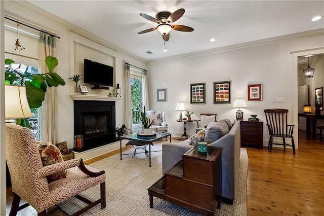 living room featuring ceiling fan, ornamental molding, and hardwood / wood-style floors