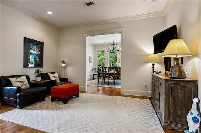 living area featuring light hardwood / wood-style floors, ornamental molding, and a notable chandelier