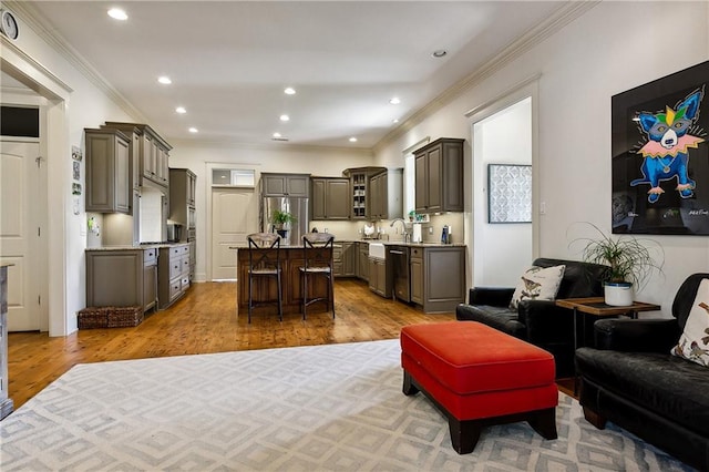 living room with sink, light wood-type flooring, and ornamental molding