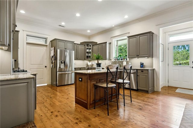 kitchen with a kitchen island, stainless steel appliances, light hardwood / wood-style floors, and a wealth of natural light