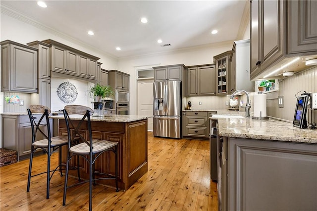 kitchen with light hardwood / wood-style flooring, stainless steel appliances, gray cabinets, and crown molding