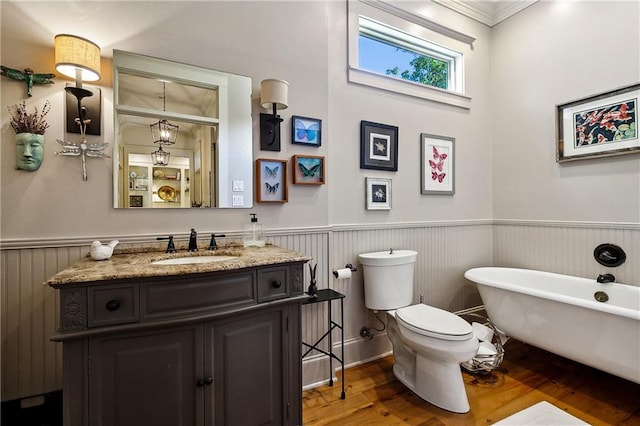 bathroom with vanity, a bathtub, toilet, crown molding, and hardwood / wood-style floors