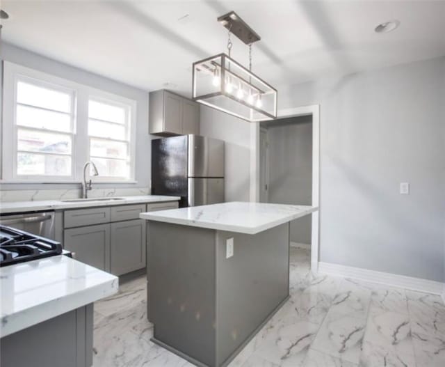 kitchen with a center island, stainless steel refrigerator, gray cabinetry, decorative light fixtures, and light stone countertops