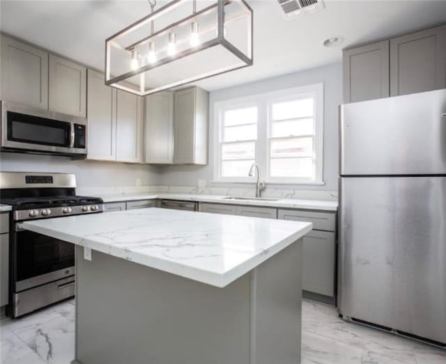 kitchen featuring light stone countertops, appliances with stainless steel finishes, sink, and a center island