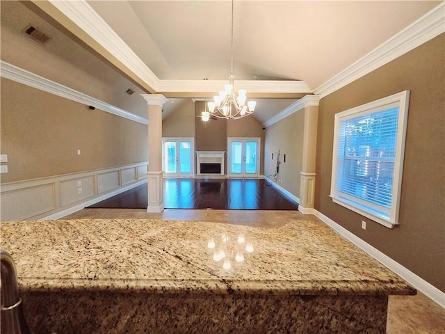 kitchen with pendant lighting, lofted ceiling, an inviting chandelier, decorative columns, and crown molding