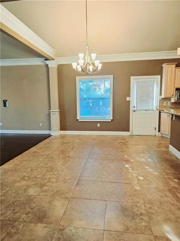 unfurnished dining area with a notable chandelier, crown molding, and decorative columns