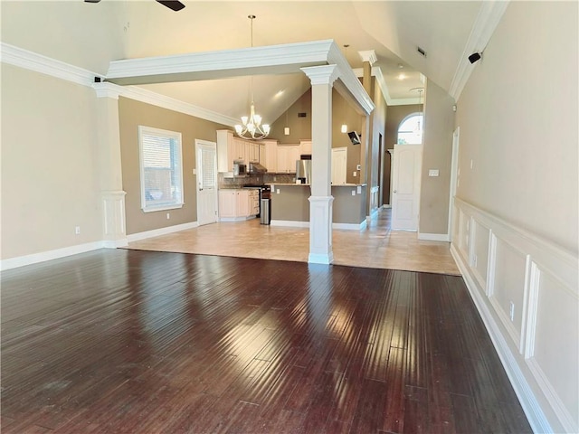 unfurnished living room featuring ceiling fan with notable chandelier, high vaulted ceiling, ornamental molding, and light wood-type flooring