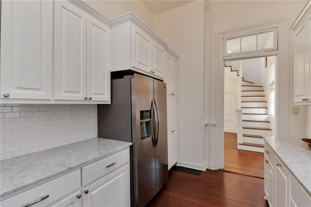 kitchen with light stone countertops, stainless steel fridge with ice dispenser, dark hardwood / wood-style floors, backsplash, and white cabinets