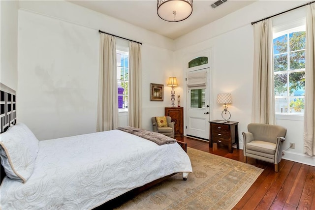 bedroom with dark hardwood / wood-style flooring and multiple windows