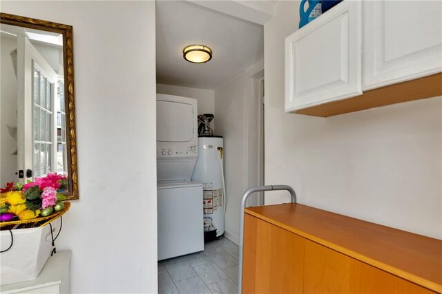 laundry room featuring water heater and stacked washing maching and dryer