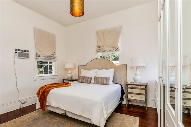 bedroom with a wall unit AC and dark wood-type flooring