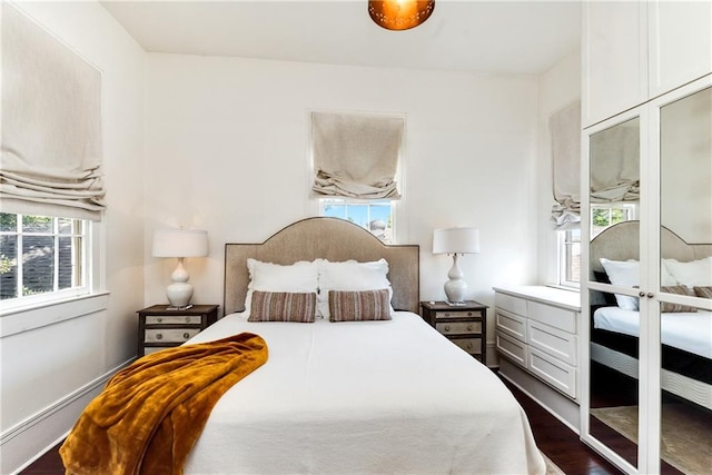 bedroom with multiple windows and dark wood-type flooring