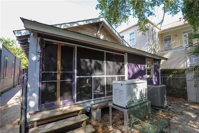 back of property with a balcony, a sunroom, and central AC