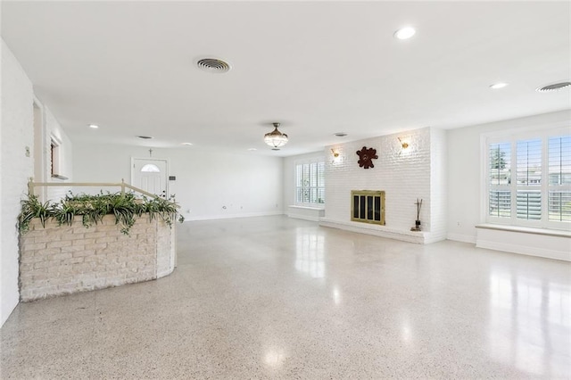 unfurnished living room with a large fireplace and a healthy amount of sunlight