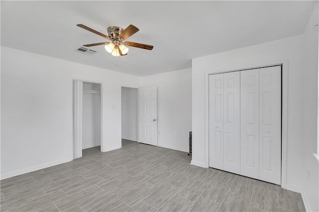 unfurnished bedroom featuring ceiling fan and multiple closets