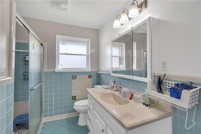 bathroom with tile walls, vanity, walk in shower, toilet, and tile patterned floors