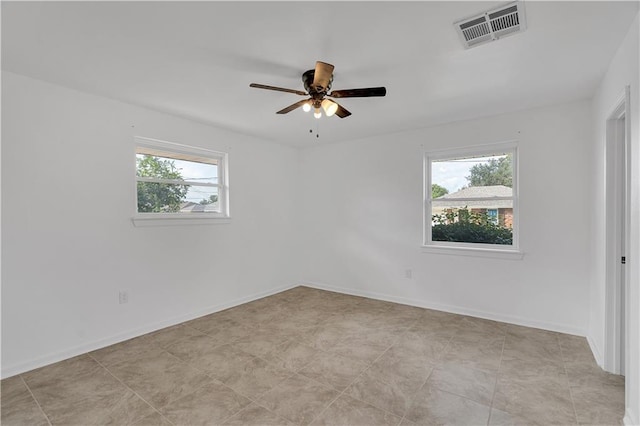 spare room with ceiling fan and plenty of natural light