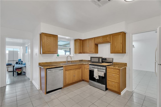 kitchen with light tile patterned floors, stainless steel appliances, sink, and light stone countertops