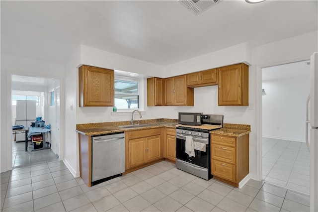 3244 Iowa Ave, Kenner, LA 70065 - kitchen with dark stone counters, a sink, light tile patterned floors, appliances with stainless steel finishes, and visible vents