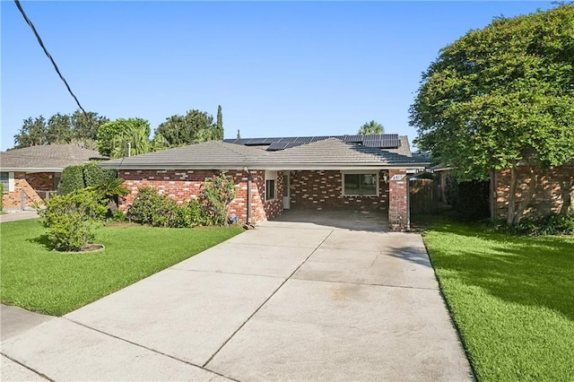 ranch-style home featuring a carport, solar panels, and a front yard