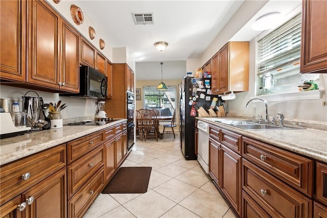 kitchen with light stone countertops, sink, pendant lighting, light tile patterned floors, and black appliances