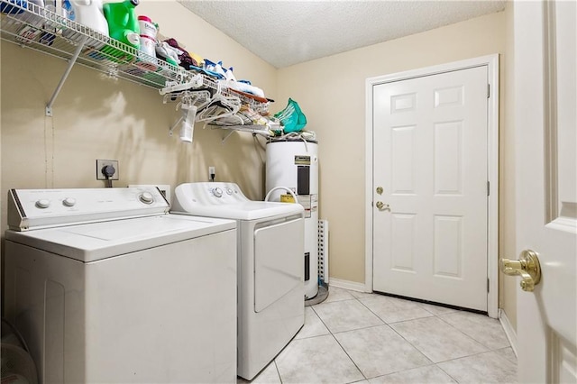 washroom with a textured ceiling, electric water heater, light tile patterned floors, and washing machine and dryer