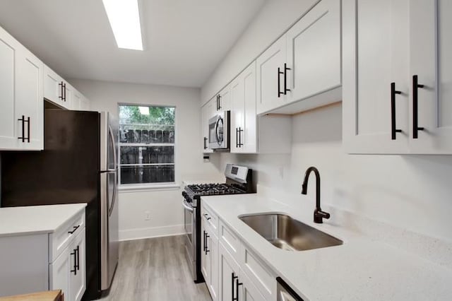 kitchen featuring appliances with stainless steel finishes, light wood-type flooring, sink, and white cabinetry