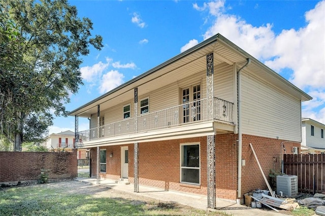 rear view of property with cooling unit, a balcony, and a patio area