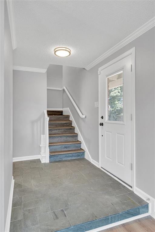 foyer entrance featuring ornamental molding and a textured ceiling