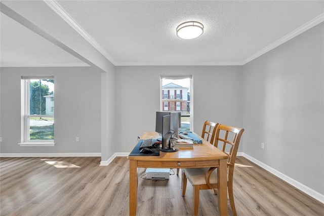 dining room with light wood-type flooring, a textured ceiling, and crown molding