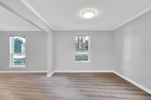 spare room with light wood-type flooring, crown molding, and a wealth of natural light