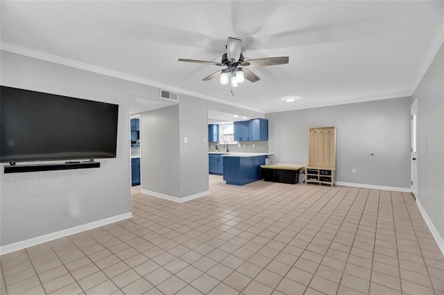 unfurnished living room featuring ceiling fan, light tile patterned floors, a textured ceiling, and ornamental molding