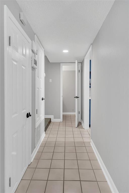 hall featuring a textured ceiling and light tile patterned floors